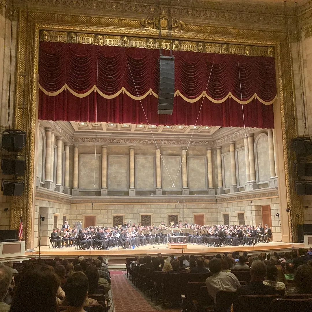Photograph of 2023 NafME All-East Band on stage: Andre is sitting second from front, second row from the left